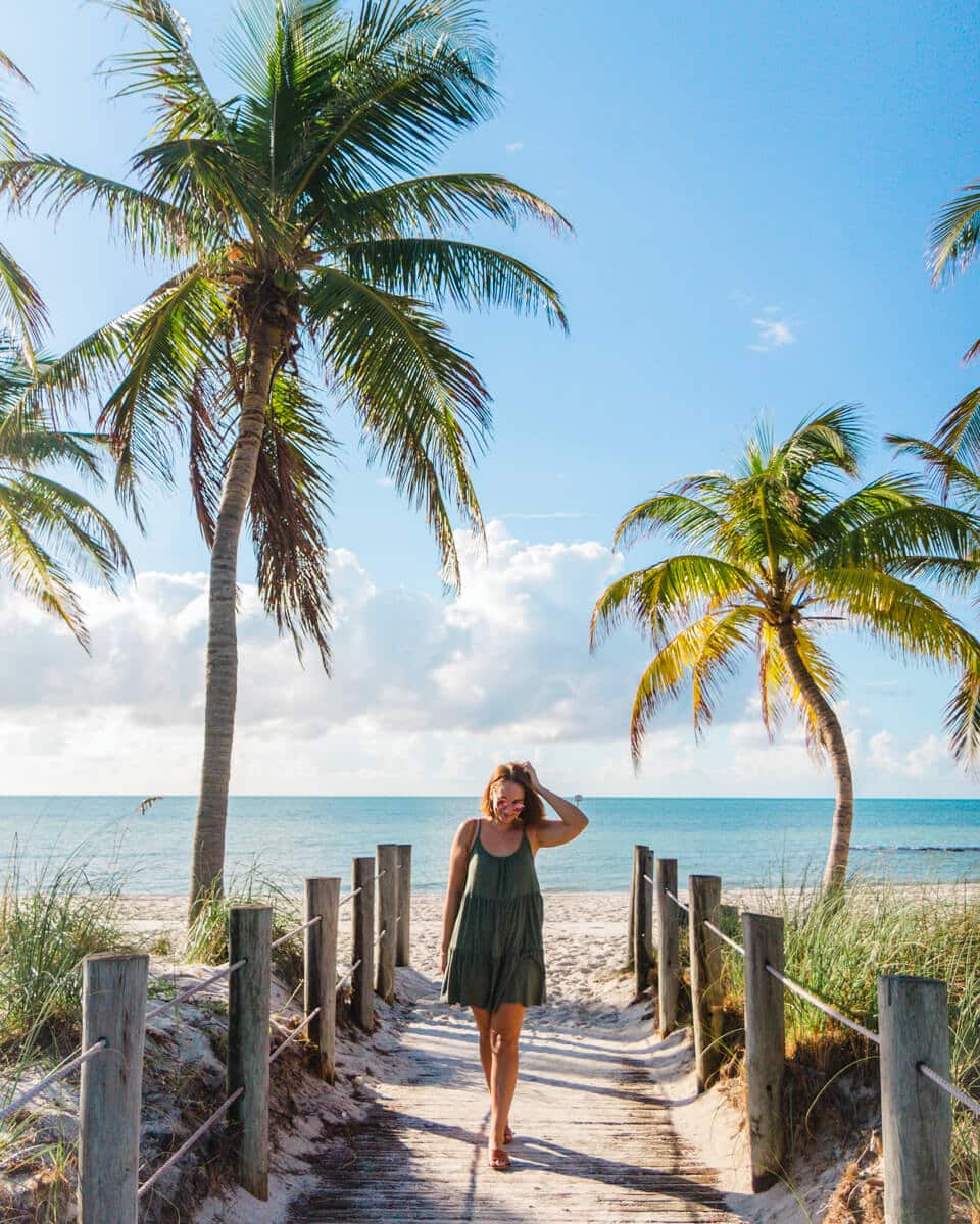 girl standing in between pam trees on Smathers Beach, Key West