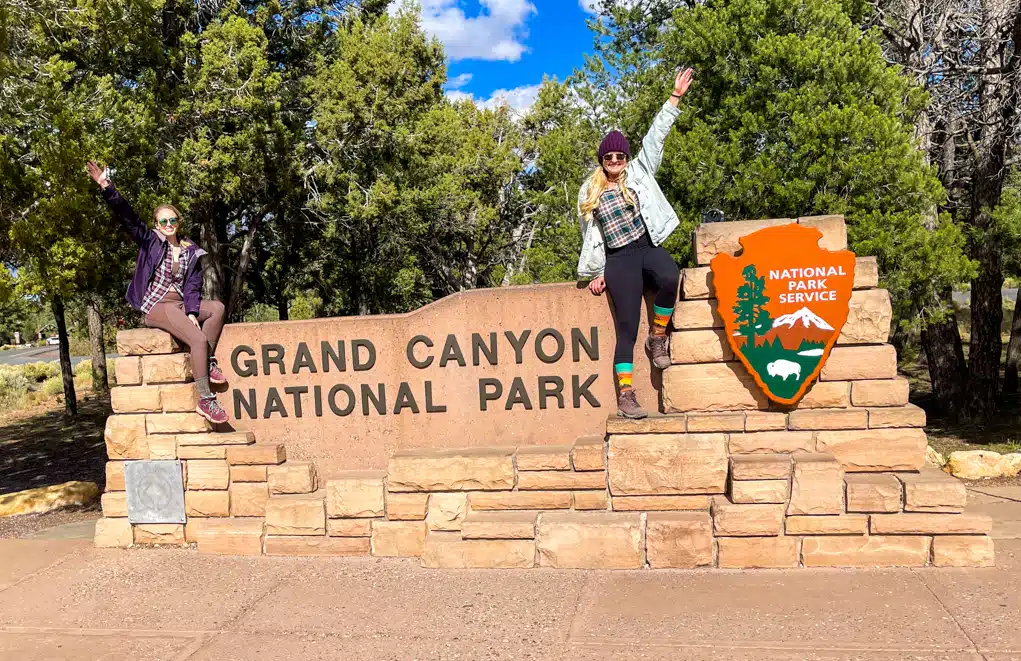 Girls sitting on top of Grand Canyon sign