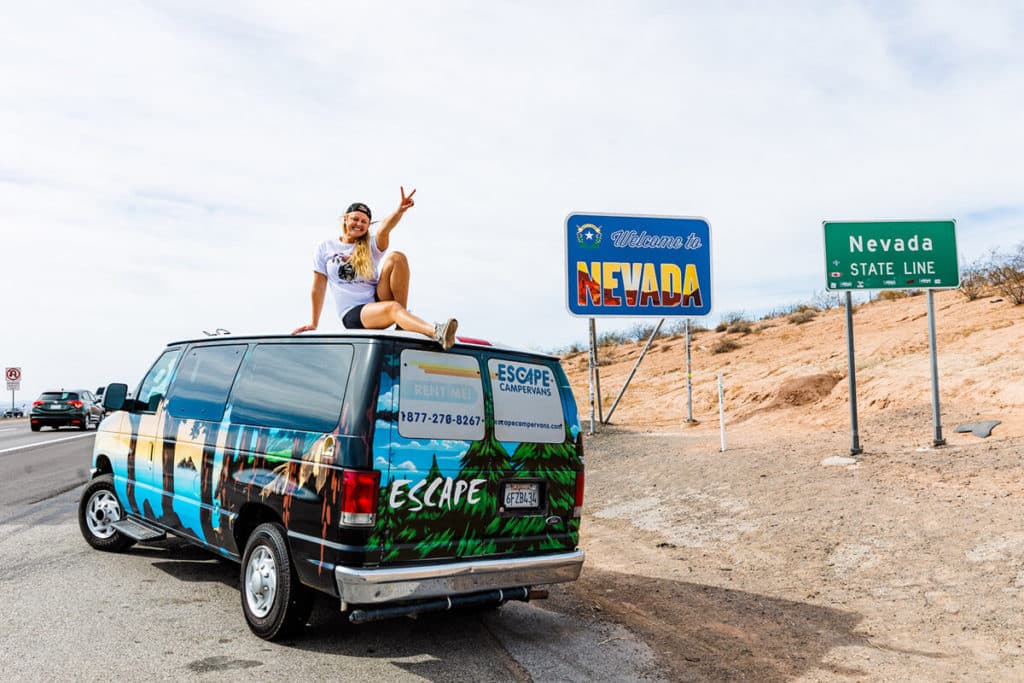girl sitting on top of van in front of Nevada sign