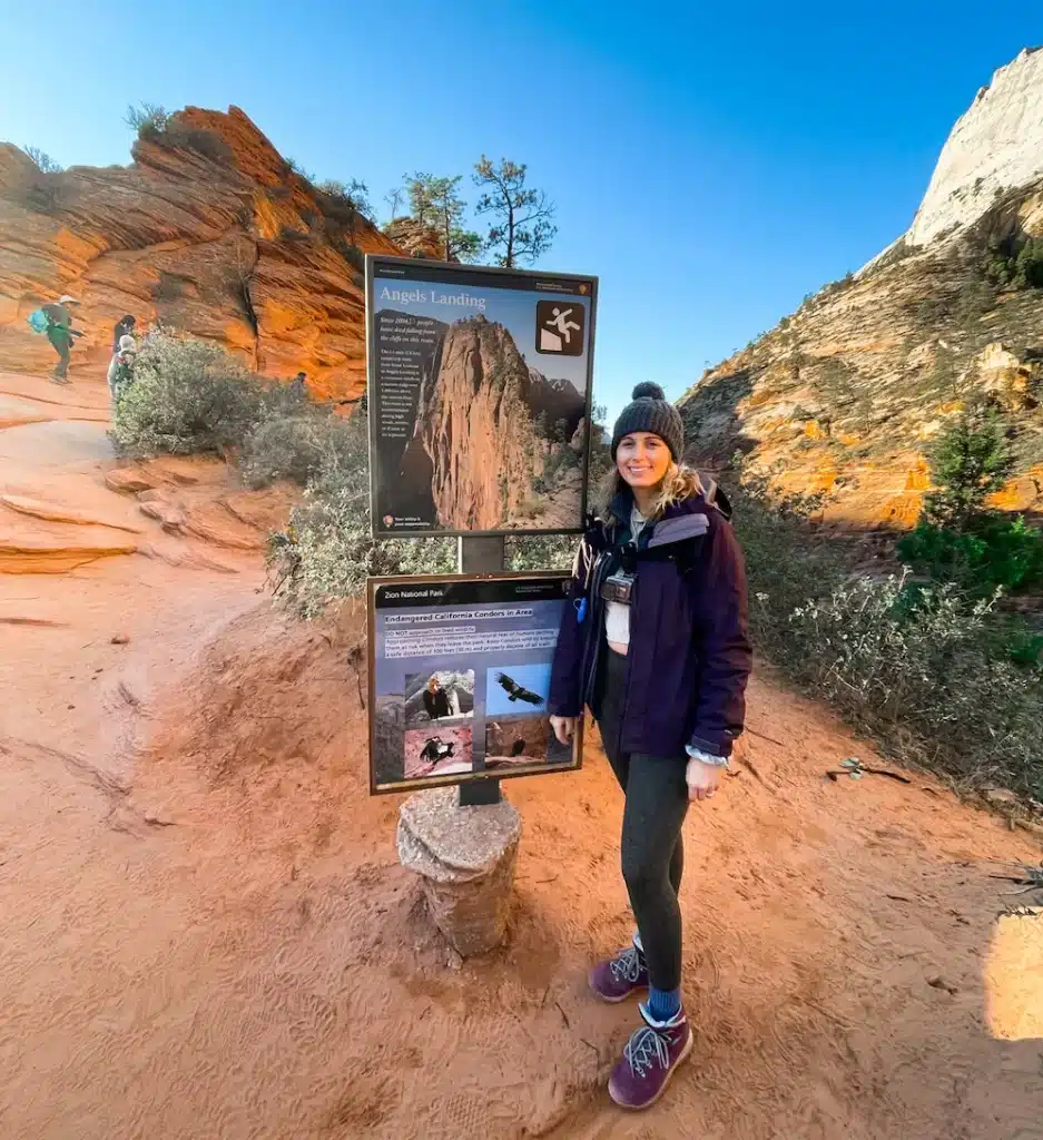 girl standing in front of Angels Landing sign