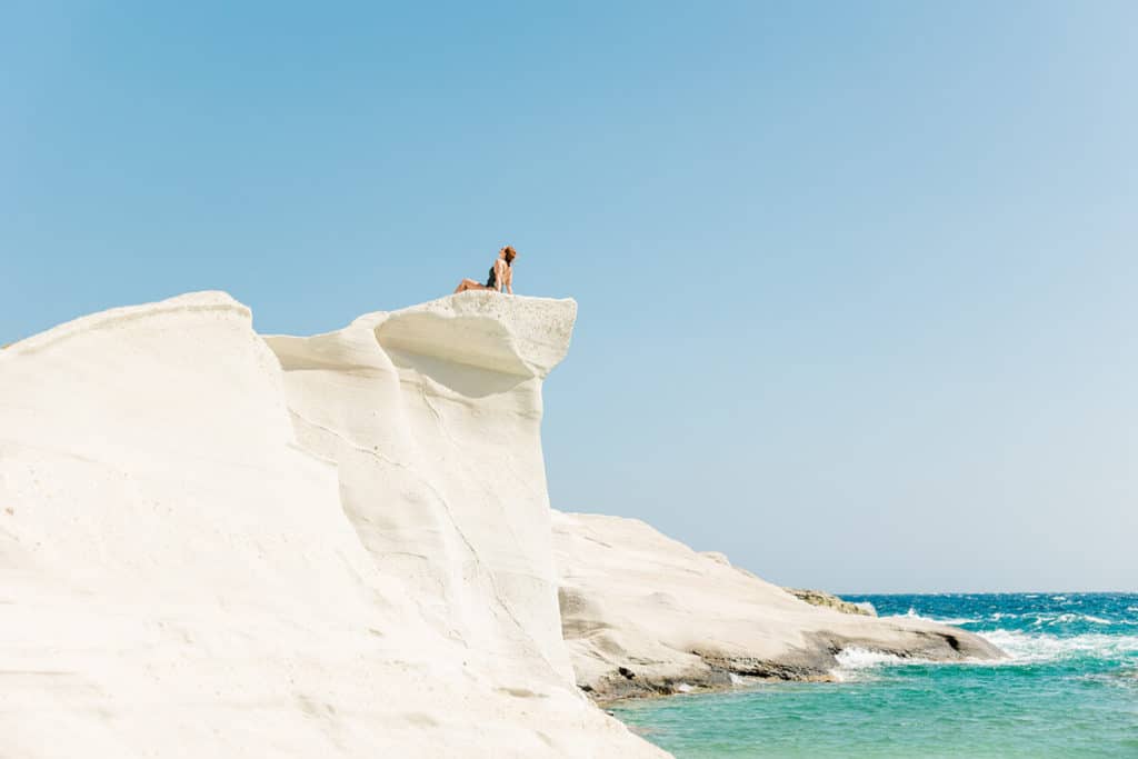 girl sitting on top of white rock at Sarakinko Beach, Milos, Greece