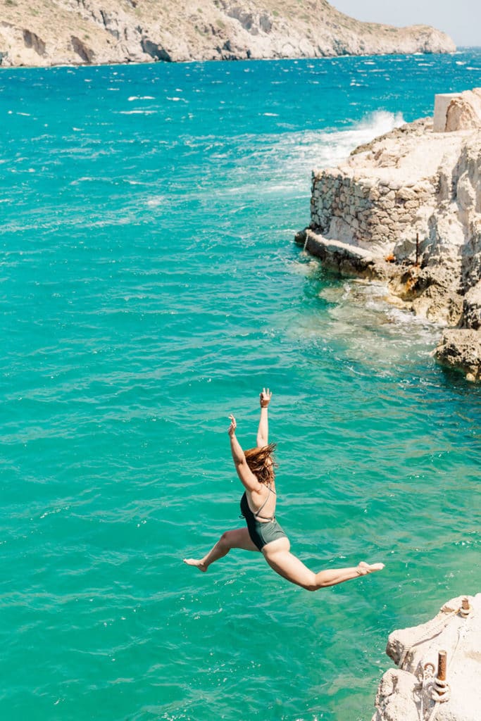girl jumping off ledge in Greece