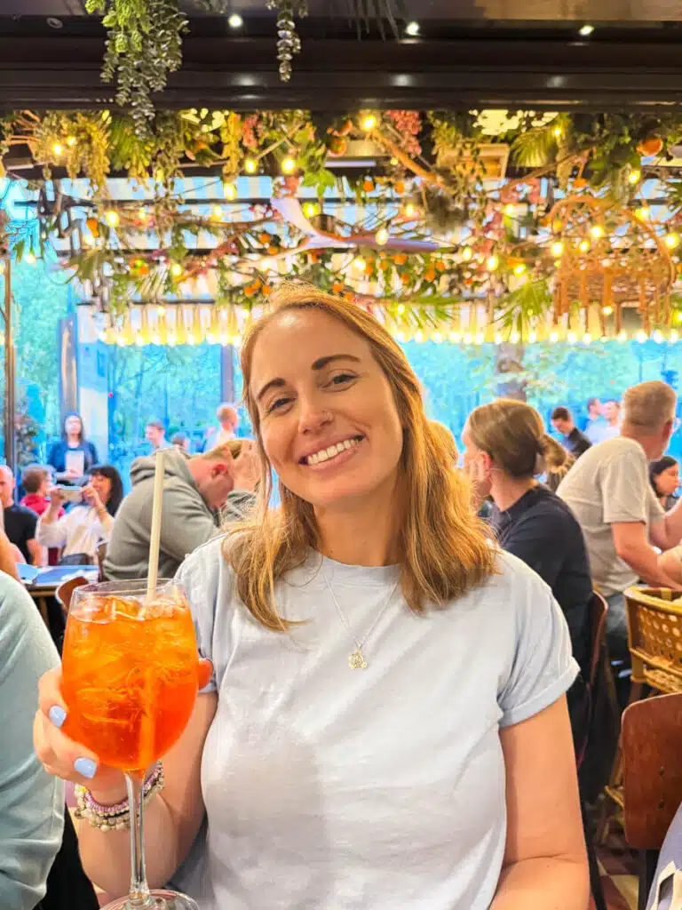 girl holding aperol spritz at a cafe in Paris