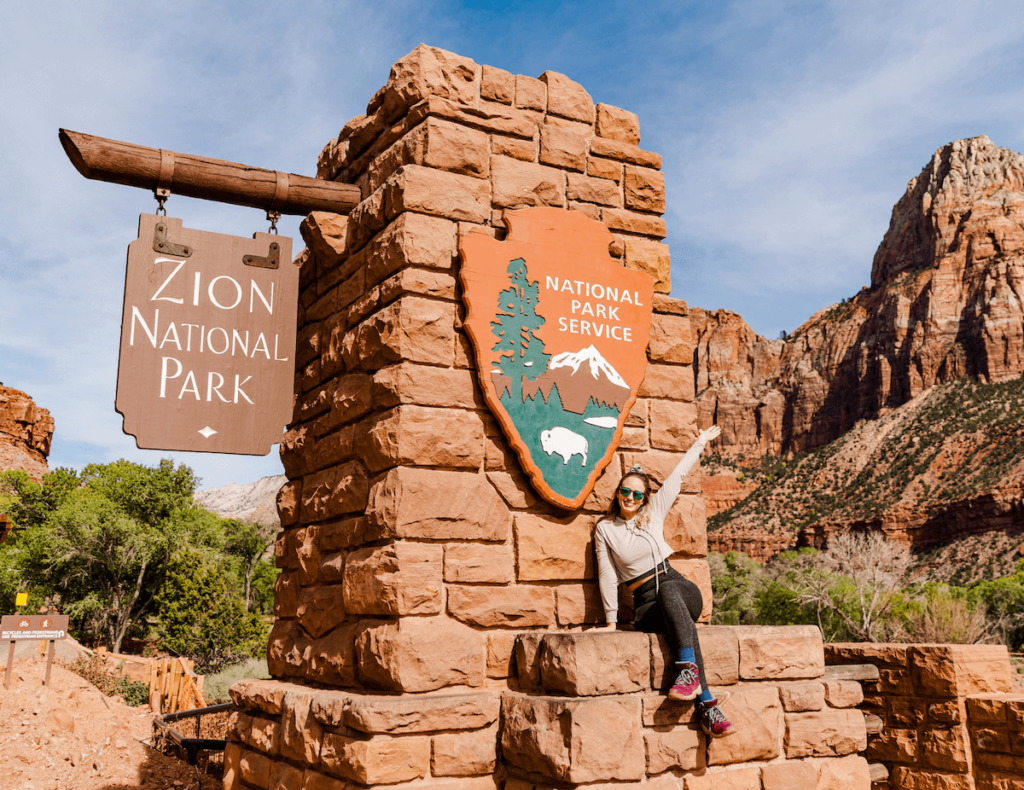 girl sitting in front of Zion sign