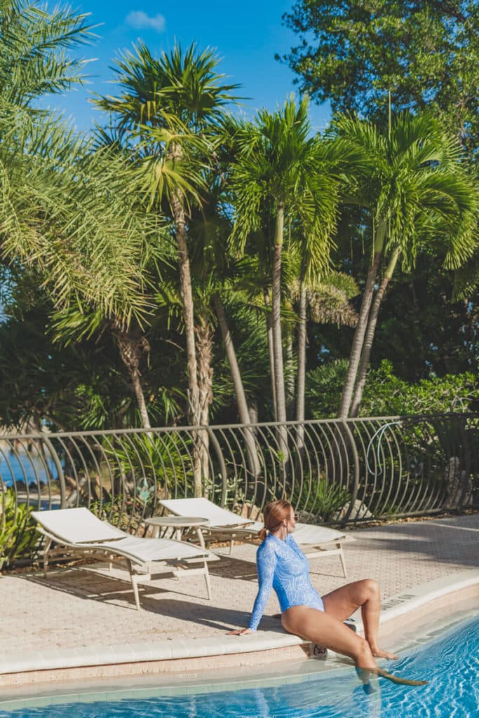 girl sitting by pool with palm trees