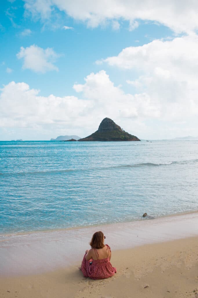 girl sitting on beach in front of Chinaman's Hat, Oahu