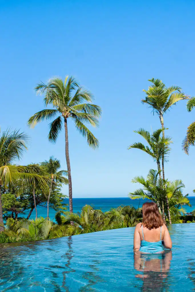 girl in infinity pool with palm trees in distance at Hapuna Beach Resort