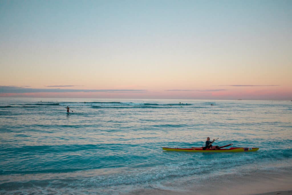 surfers and kayakers on Waikiki beach at sunrise