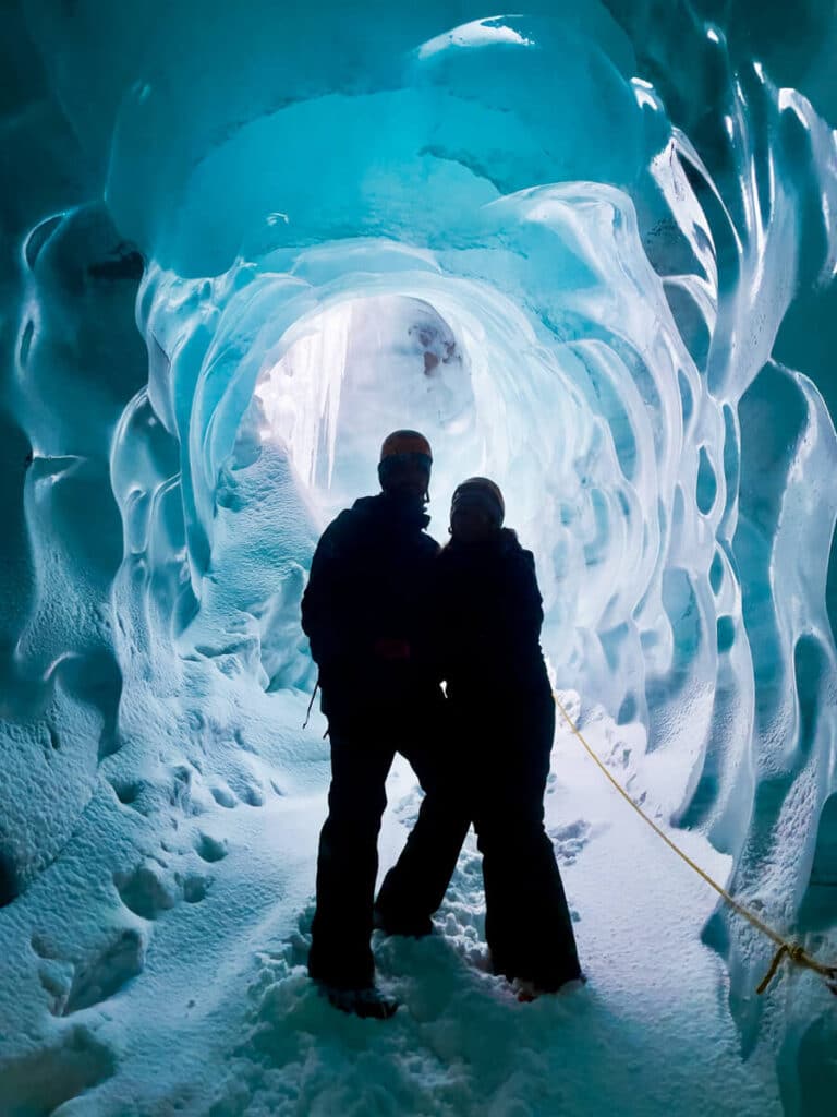 couple standing in front of Katla Ice Cave in winter Iceland