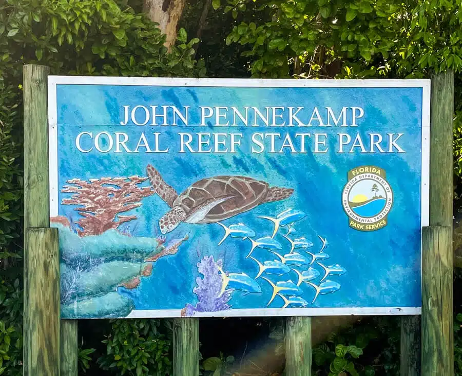blue sign with turtles and sea life marks the entrance to John Pennekamp Coral Reef State Park in Key Largo Florida