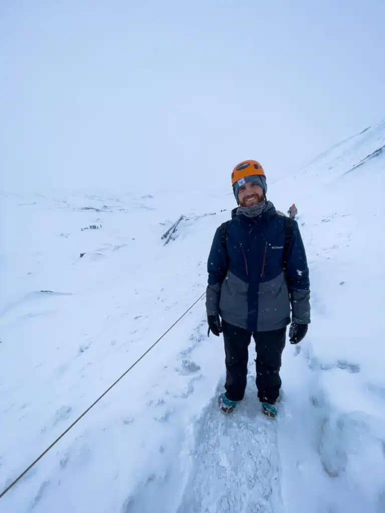 man standing on snowy ledge smiling at the camera in Iceland