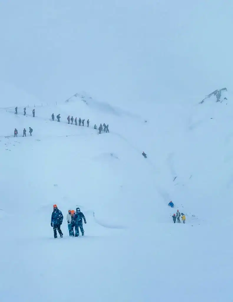 people sliding down the side of a snowy mountain on a Katla Ice cave tour in Iceland