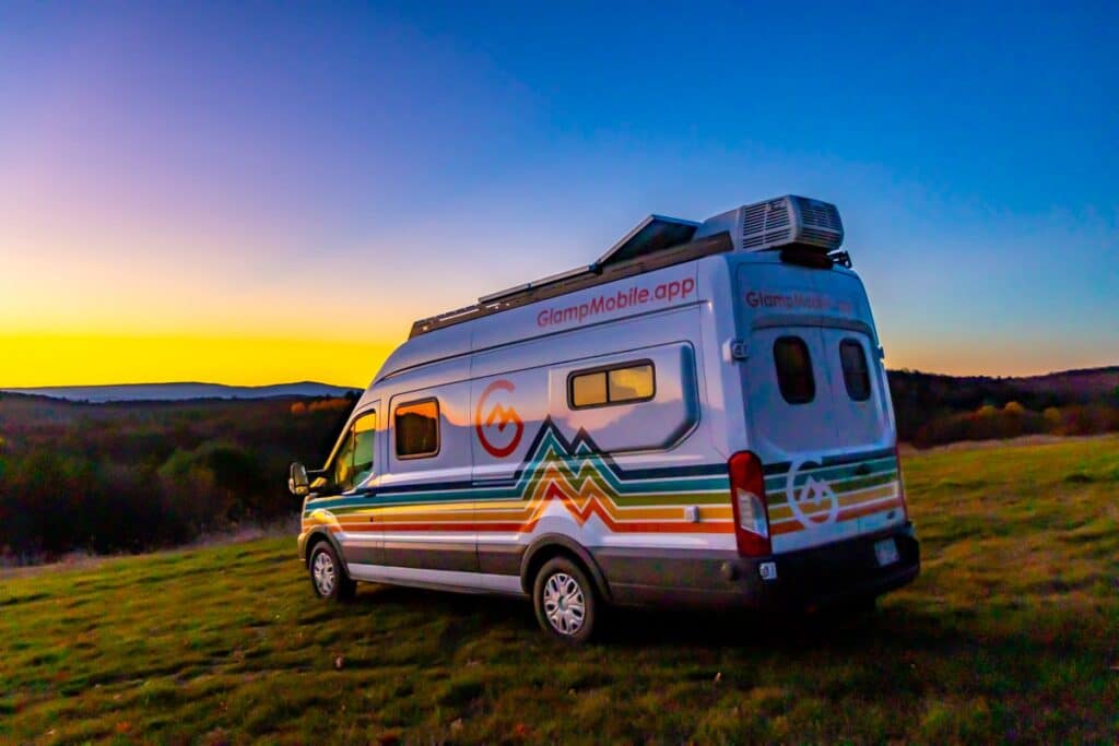 campervan parked on hill with blazing sunset in background outside of Woodstock, Vermont