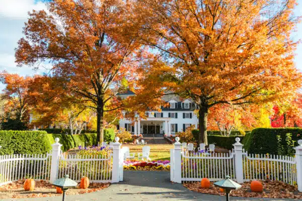 Front of Woodstock Inn in Woodstock Vermont with large orange trees. The Woodstock Inn is one of the best places to stay in Vermont during fall.