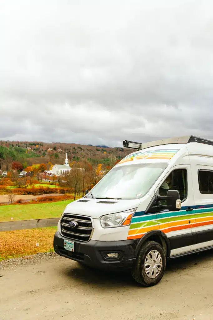 van with colorful stripes on hillside in front of Stowe Vermont