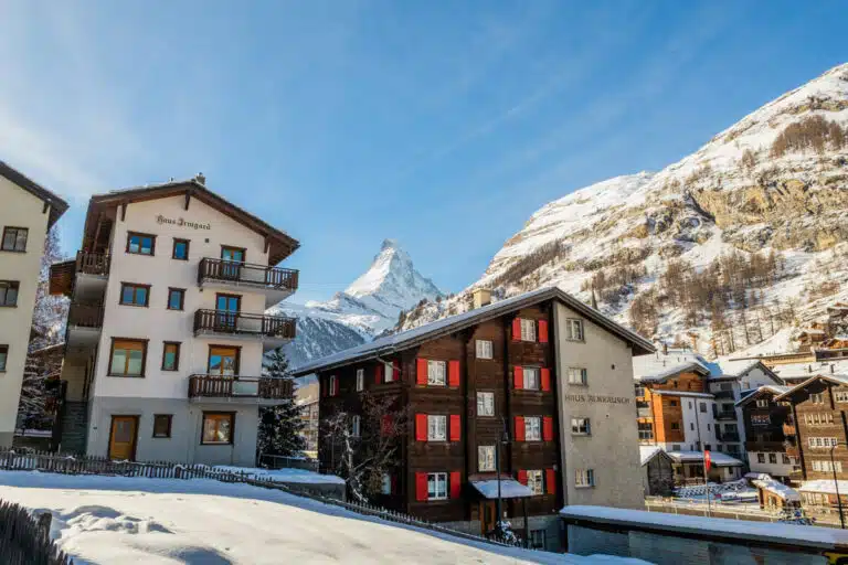 brown and tan wooden hotels in front of Matterhorn with blue skies in Zermatt, Switzerland