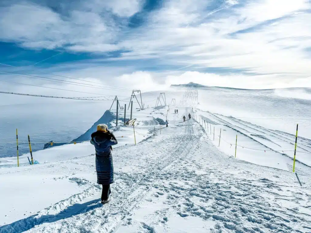 girl walking along snowy path above the clouds at the top of Matterhorn Glacier Paradise in Zermatt Switzerland
