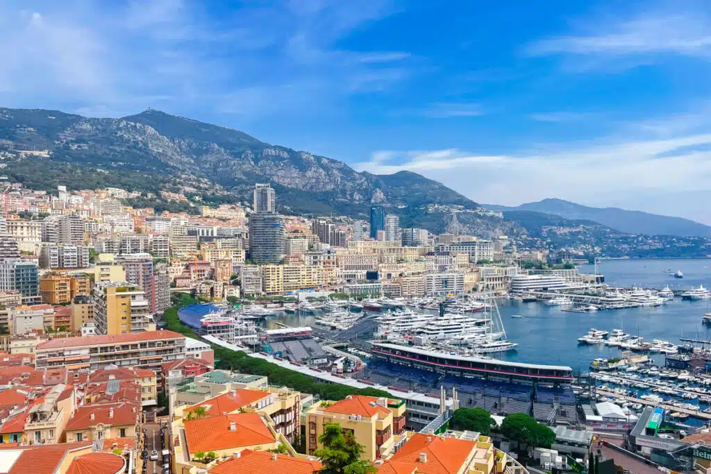 A sweeping view of Monaco’s yacht-filled harbor and densely packed buildings nestled against the mountains, taken during a sunny day trip to Monaco from Nice.