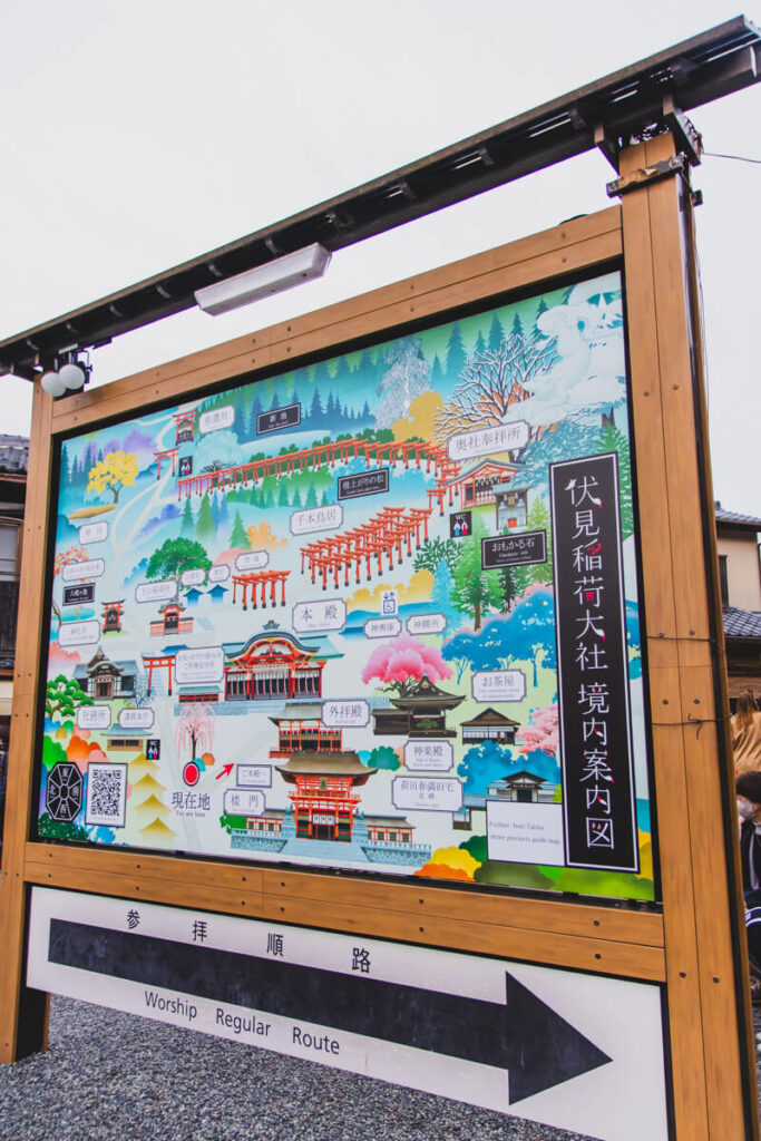 A detailed, illustrated map of the Fushimi Inari Shrine complex showing the network of torii gate trails, shrine buildings, and hiking routes, with directional signage for visitors.