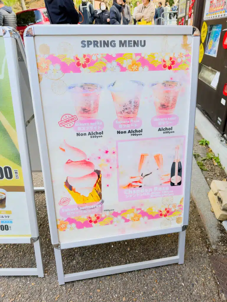 A vibrant spring menu display showing seasonal treats like sakura sprite, sakura float, and sakura soft serve, highlighting limited-edition offerings popular during sakura season in Japan.