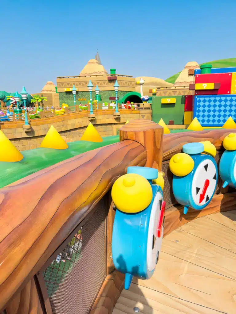 Yellow and blue alarm clocks mounted to wooden posts inside Super Nintendo World at USJ.