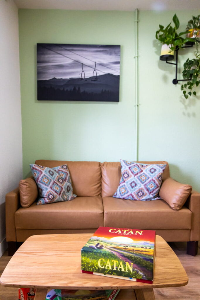 wooden table with catan board game box on top of it with couch and pillows in background. This is the common area at Tahoe Mountain Inn