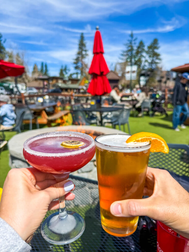 hands holding a martini and beer cheers in front of the patio and firepit at California Burger Company in South Lake Tahoe