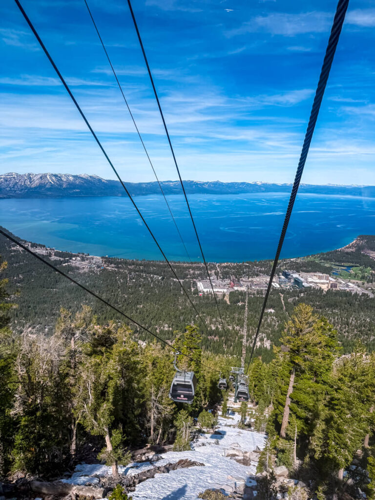 view of Heavenly gondola looking down with sprawling greenery and Lake Tahoe in the background