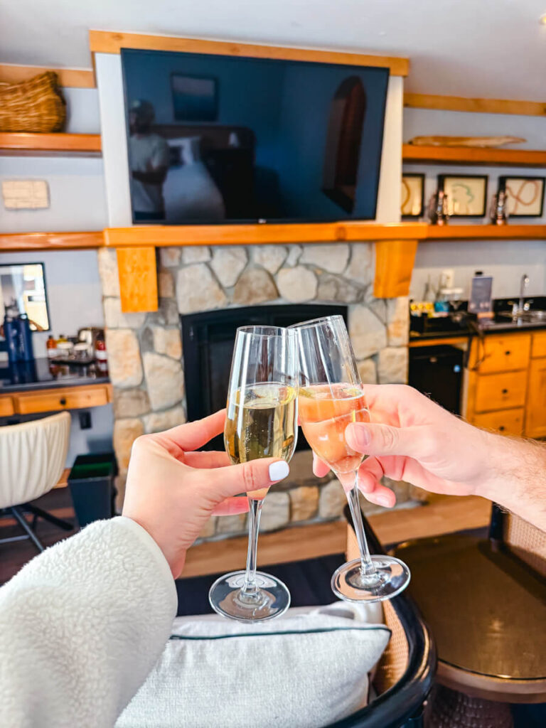 two hands hold champagne glasses, cheers-ing inside a room at the Landing Resort and Spa in Lake Tahoe