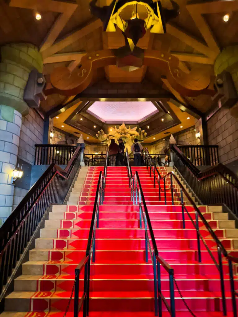 Interior staircase at Universal Studios Japan in Osaka inside Bowser’s Castle featuring bright red steps leading up to a large Bowser statue under warm lighting.