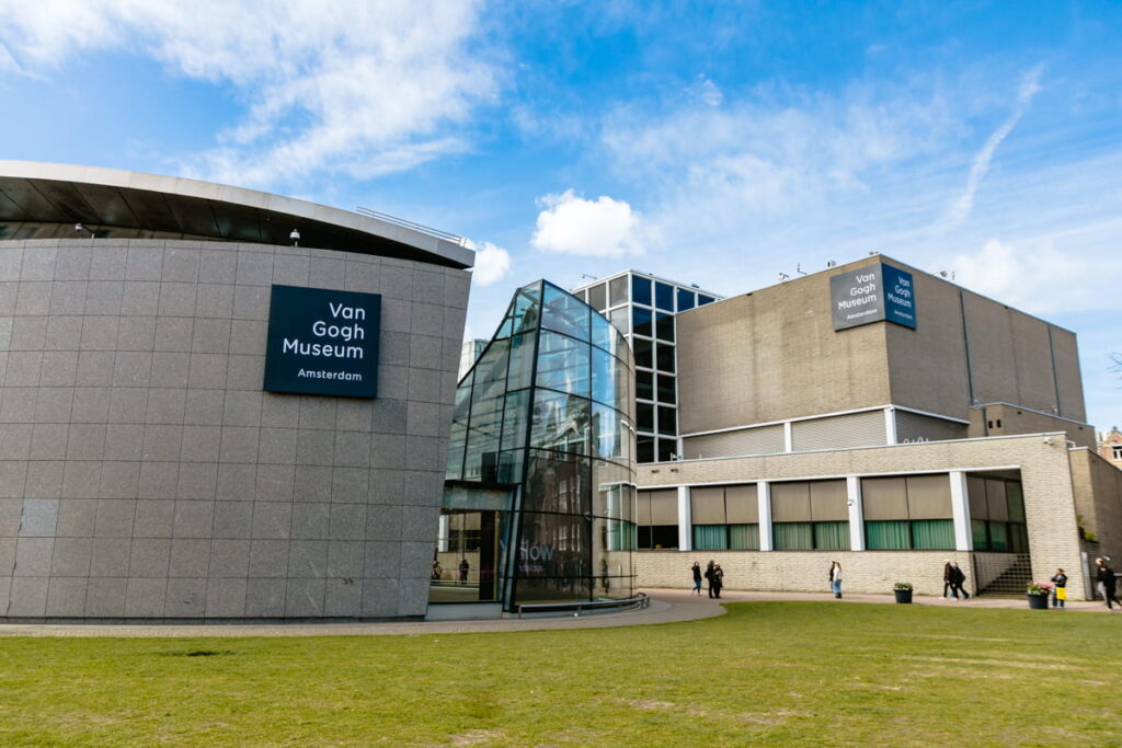 Modern exterior of the Van Gogh Museum in Amsterdam with its curved glass entrance and large sign on a gray stone building. This museum houses the world’s largest collection of Van Gogh’s artwork.