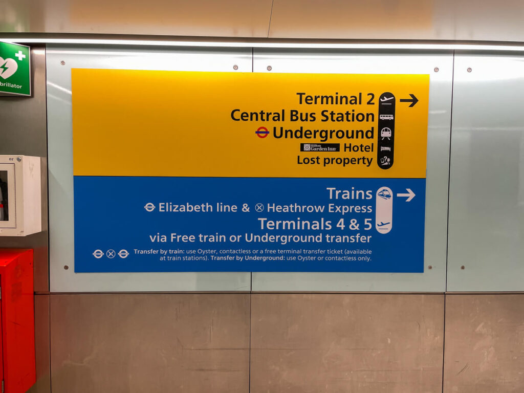 Heathrow Airport sign pointing to the Underground and Central Bus Station, plus the Elizabeth line, Heathrow Express and free transfer train to Terminals 4 and 5