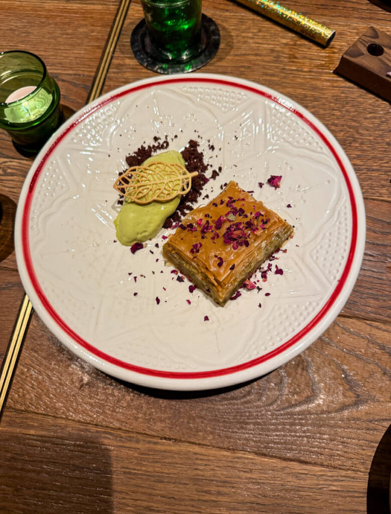 Baklava topped with rose petals next to a scoop of pistachio ice cream at Bazaar restaurant in Zermatt