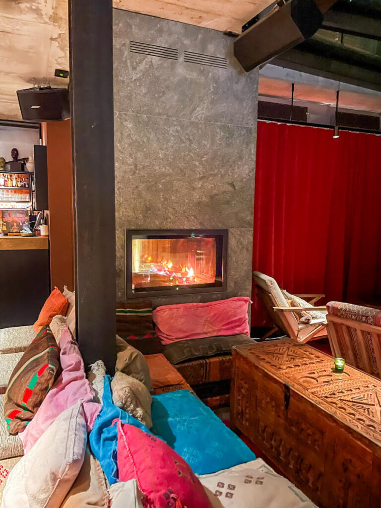 Cozy fireplace lounge with colorful cushions and a carved wooden chest at Bazaar at CERVO Mountain Resort in Zermatt