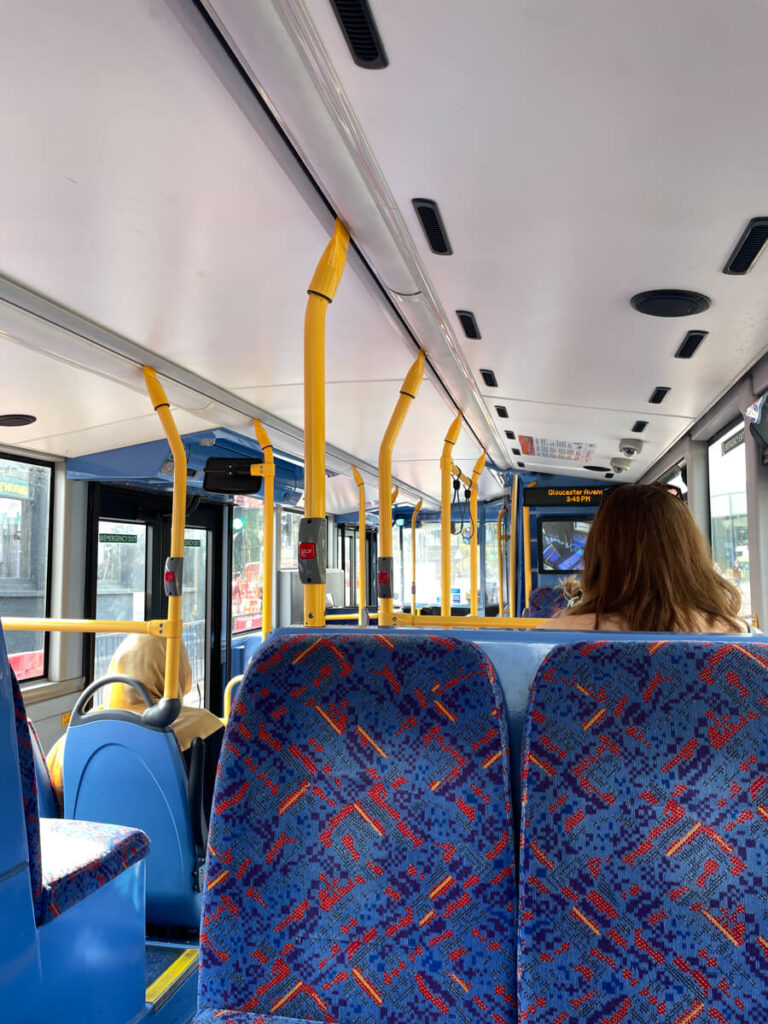 Inside a red London double-decker bus with patterned blue seats and yellow handrails