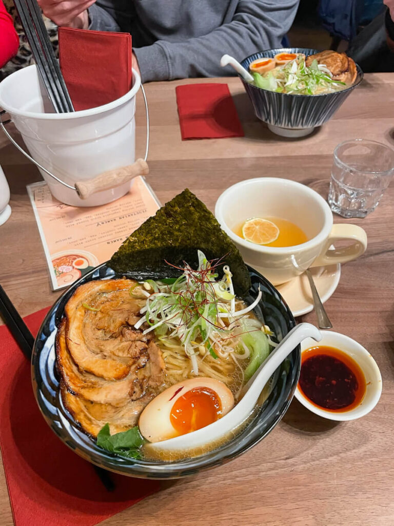 Bowl of ramen with pork, soft-boiled egg and nori, served with a cup of tea at MANUD in Zermatt